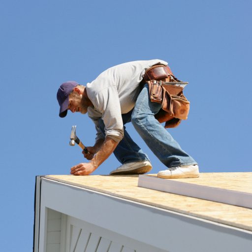 Zimmermann, der gerade einen Nagel einschlägt, auf einem Dach